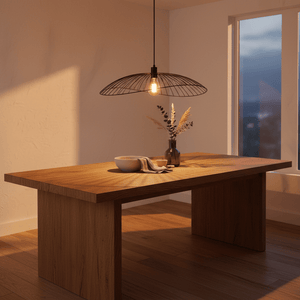 Stylish black pendant light hanging above a wooden dining table with decorative vase and bowl.