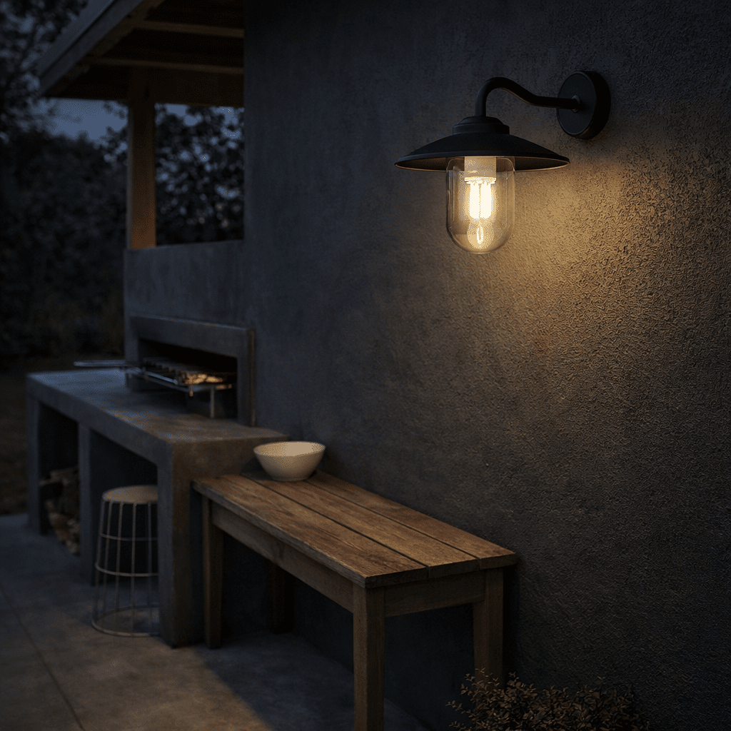 Black metal and glass outdoor wall light illuminating a patio area with wooden furniture.