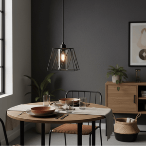Stylish metal pendant light with smoked glass shade hanging above a dining table set with plates and glasses.