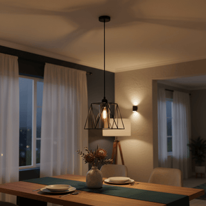 Stylish metal pendant light with smoked glass shade hanging over a dining table set with plates and a vase.