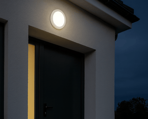 Round outdoor light fixture on a house exterior at night