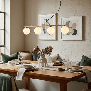 Linear 4 Light Pendant in gold above a dining table set with dishes and glassware, featuring decorative elements.