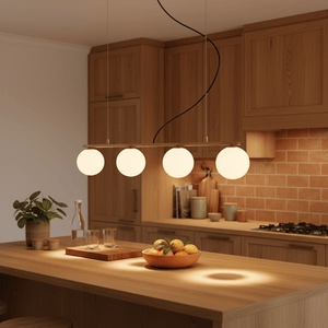 Linear 4 Light Pendant in gold above a kitchen island, illuminating a bowl of fruit and glasses.