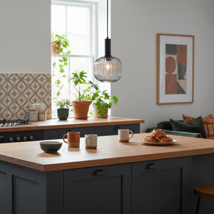Jackie Smoke Cut Glass Pendant light hanging above a kitchen island with mugs and pastries.