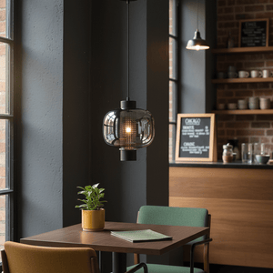 Chicago Medium Black Glass Pendant light hanging above a wooden table with green chairs and a potted plant.