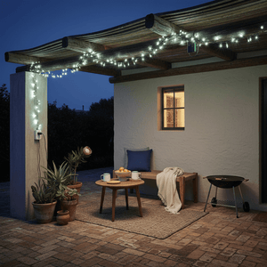 LED fairy lights draped over a patio, illuminating a cozy seating area with a table and plants.