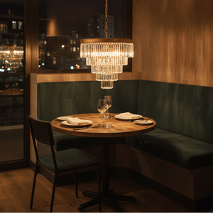 Satin gold 5-tier crystal chandelier hanging above a wooden dining table set for two.
