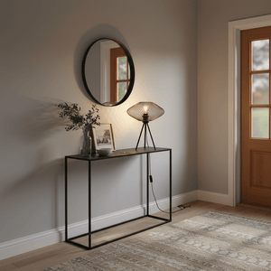 A stylish black mesh table lamp on a console table, next to a mirror and decorative items, creating a cozy ambiance.