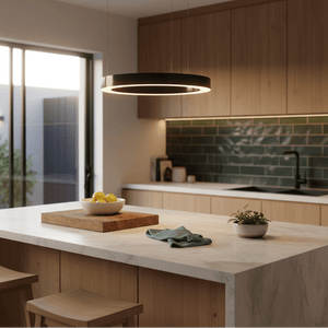 A small black LED halo pendant light hangs above a kitchen island with a bowl of lemons and a green dish towel.
