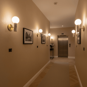 Elegant hallway featuring multiple marble wall lights, framed pictures, and an elevator.