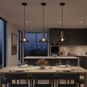 Three pendant lights with mesh and stone shades hang above a dining table set for a meal, creating a warm ambiance.