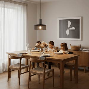 Industrial-style pendant light hanging over a wooden dining table with children enjoying a meal.