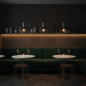 Industrial-style pendant lights illuminate a cozy dining area with green seating and marble tables.