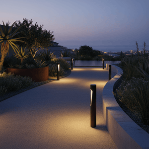 Cato LED bollard lights illuminating a curved outdoor pathway surrounded by plants at dusk.