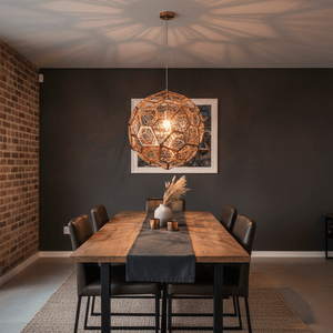 Alberta Geo Copper Pendant Light hanging over a wooden dining table, casting intricate shadows on the wall.