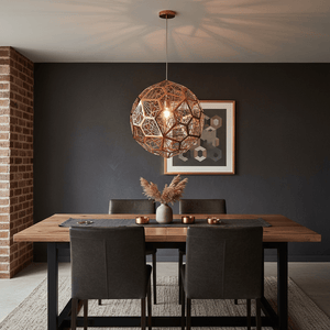 Alberta Geo Copper Pendant Light hanging above a wooden dining table with dark chairs and decorative elements.