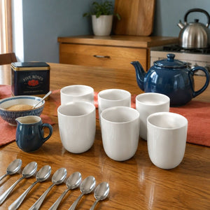 Six plain white handleless ceramic cups arranged for morning tea