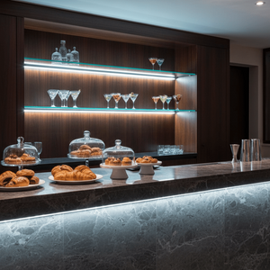 LED striplight illuminating a stylish bar counter with pastries and glassware on display.