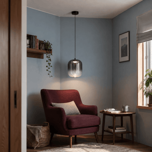 Black smoky-glass LED pendant light in a home reading corner