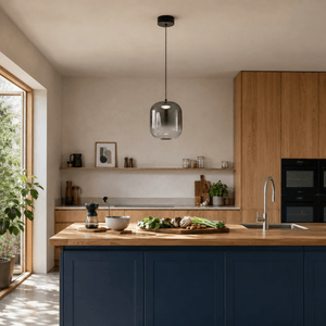 Black smoky-glass LED pendant light above a petrol-blue kitchen island