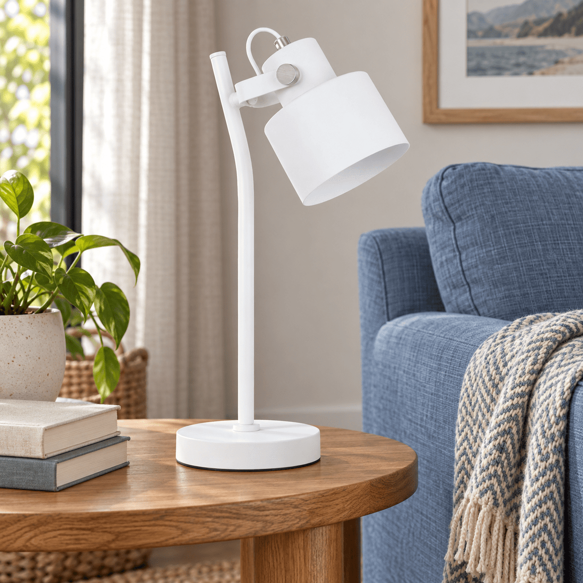 Orka white table lamp on a side table beside a dusty blue sofa