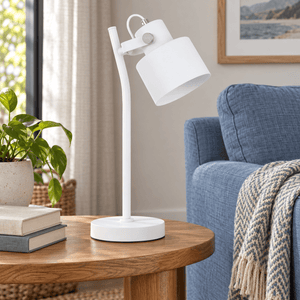 Orka white table lamp on a side table beside a dusty blue sofa
