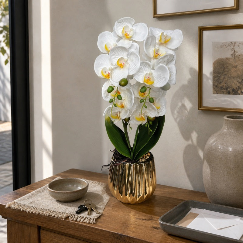 Artificial white Phalaenopsis orchid in reflective gold fluted pot on an oak entrance console