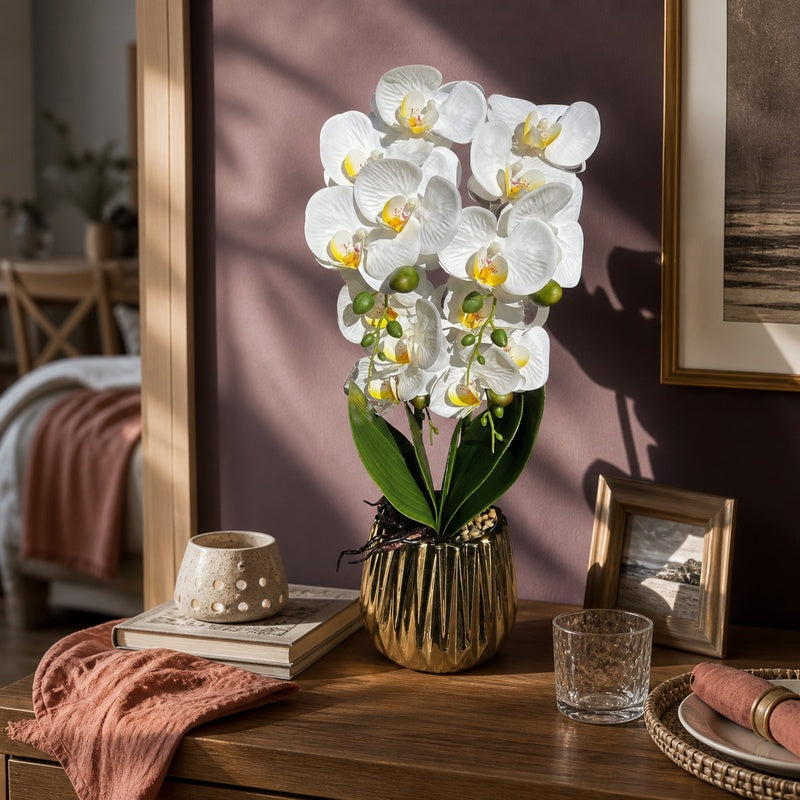 Artificial white Phalaenopsis orchid in gold fluted pot on a plum-toned dining console