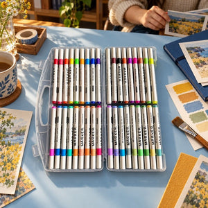 Acrylic markers box of 36 open on a powder-blue studio desk beside colour swatches