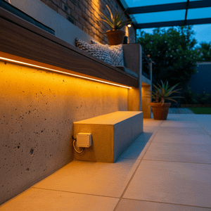 Detail view of a seamless 24V COB LED strip light installed under a wooden shelf, illuminating a concrete bench.