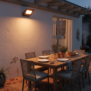 Outdoor dining area illuminated by a warm light from a mounted floodlight, featuring a wooden table set for dinner.