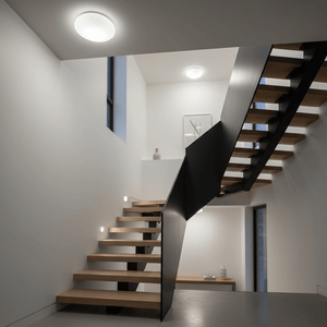 Stylish flush ceiling light illuminating a modern stairwell with wooden steps and minimalist decor.
