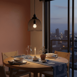 Stylish metal pendant light illuminating a dining table set with plates and a candle, against a city view.