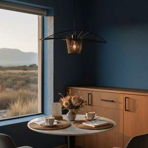 Sensu Infinite Black Pendant Light hanging above a dining table with coffee cups and flowers, set against a blue wall.