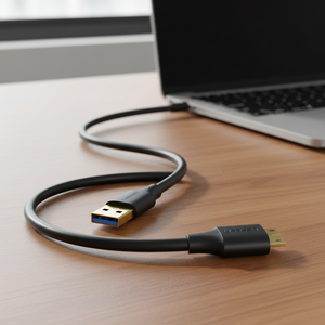 UGREEN USB to Micro USB cable laid on a wooden desk, connecting to a laptop.